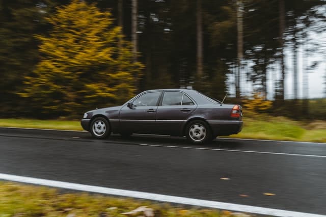 A gray car traveling at high speed on an asphalt road